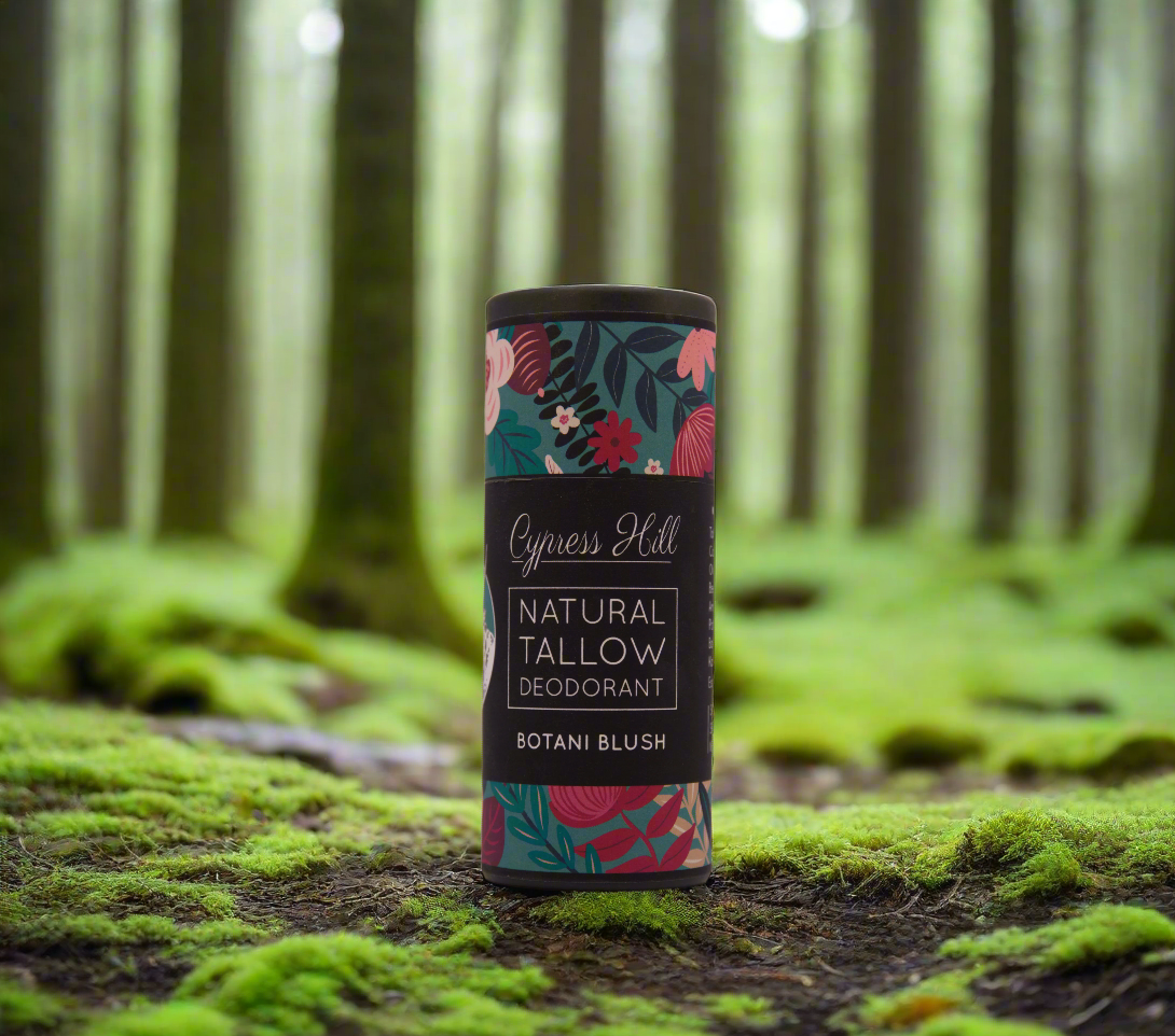 Cylindrical natural tallow deodorant container with floral design on a light gray background