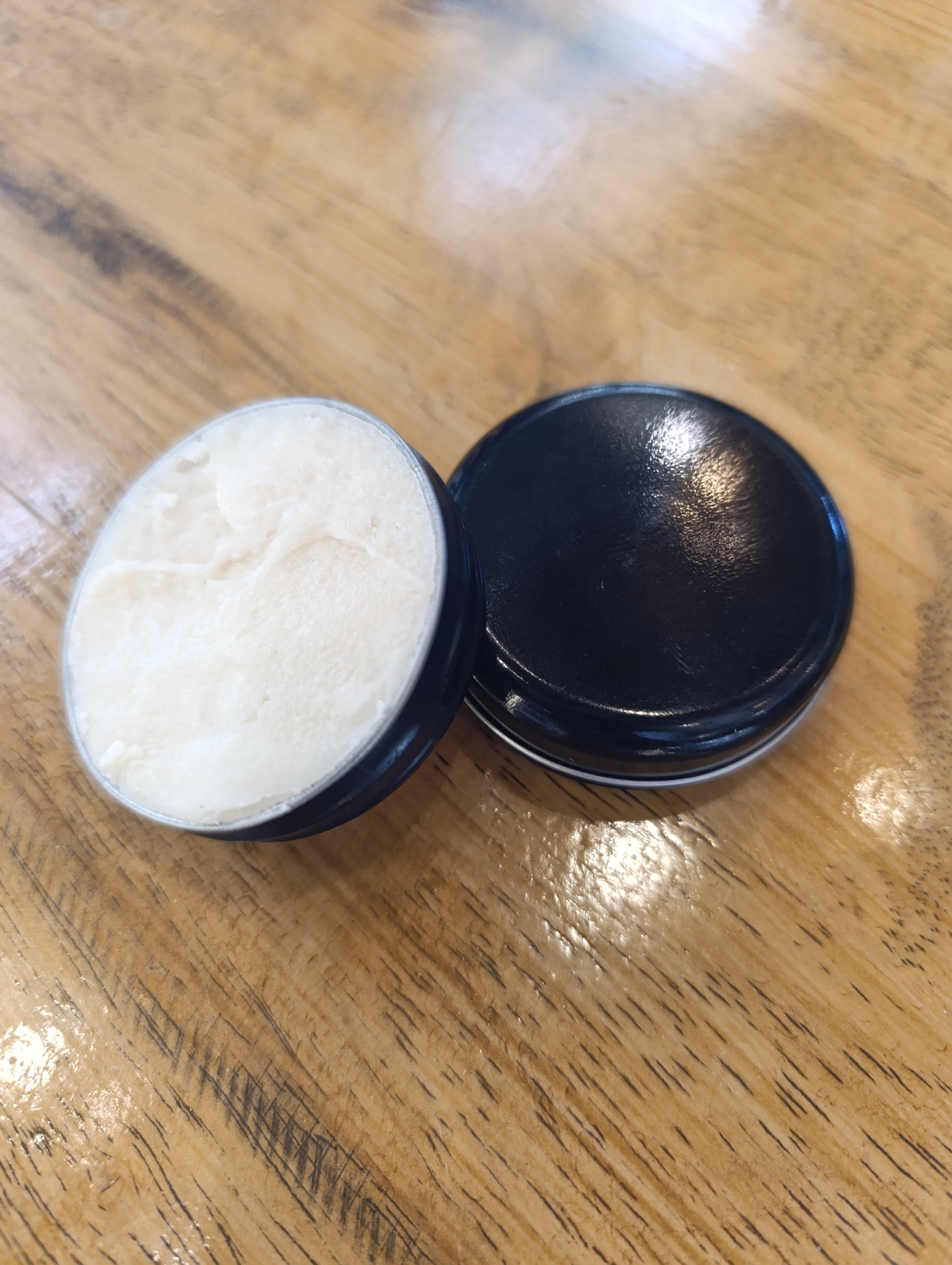 Black container with white substance on a wooden surface